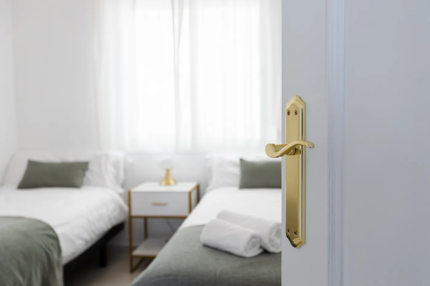 Gouden deurklink met een opgemaakte slaapkamer op de achtergrond